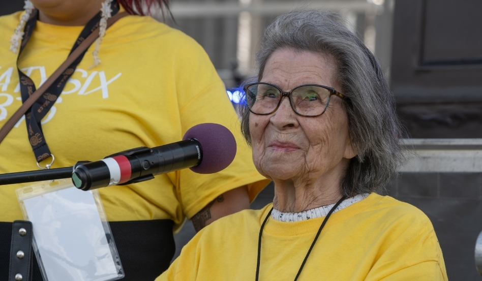 An older women sitting down with a microphone in front of her